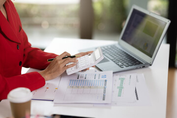 Concept of business office woman working,Closeup businesswoman checking her invesment plan with analyzing document and business investment graph data by using calculator and laptop