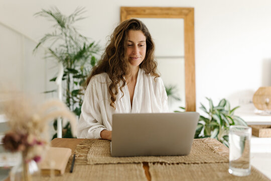 Portrait of happy young woman using laptop at home