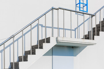 Concrete stairs installed on a white building wall.