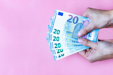 Woman's hand hold money EURO banknotes on pink background and space for text.Group of money EURO banknotes isolated.Exchange money,  Cash, finance, Money background, EURO currency and Travel concept. 