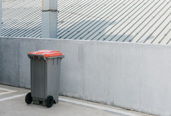 Trash can next to a concrete fence.