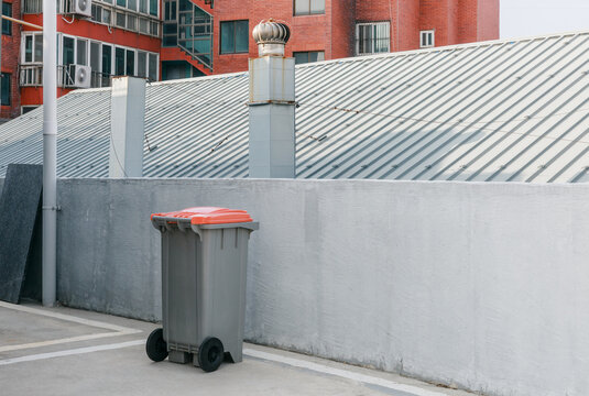 Trash can next to a concrete fence of a building.