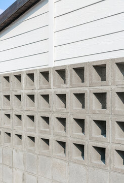 Concrete fence with square holes and white building.