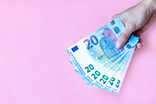 Woman's hand hold money EURO banknotes on pink background and space for text.Group of money EURO banknotes isolated.Exchange money,  Cash, finance, Money background, EURO currency and Travel concept. 