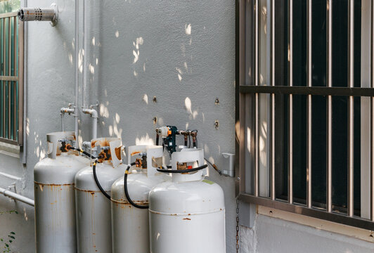 Gas cylinders and tree shadows installed next to the building wall.