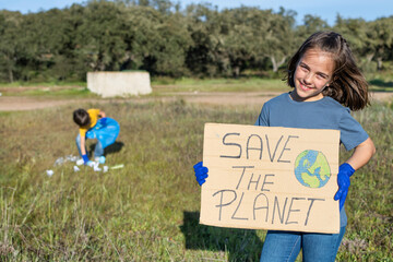 Show Up For Cleaning Service. Children Collecting Garbage From A Field And Holding A Sign That...