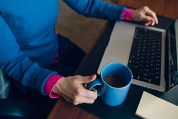 hand of woman holding mug at desk