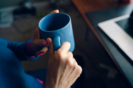 hands of woman holding mug at office desk 