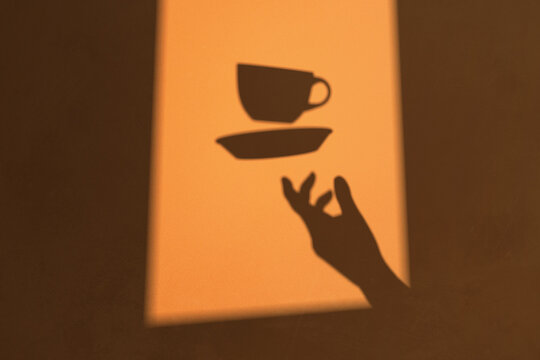 Shadow of a hand throwing a cup of coffee into the air