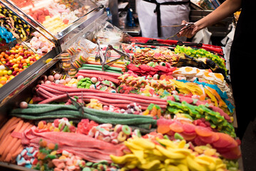 Woman picking candy at colourful market