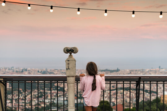 Girl looking at the city next to binoculars 