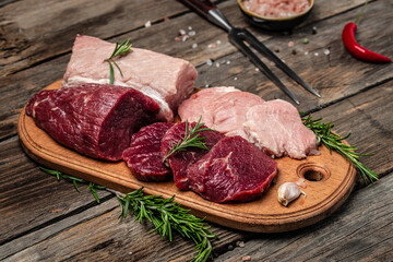 raw pork meat and beef with rosemary and spices on a wooden board. Restaurant menu, dieting, cookbook recipe. place for text