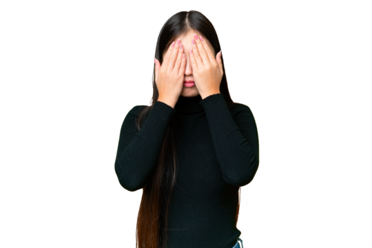 Young Asian woman over isolated chroma key background covering eyes by hands