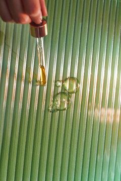 Dropper with a falling drop of aromatherapy oil close-up