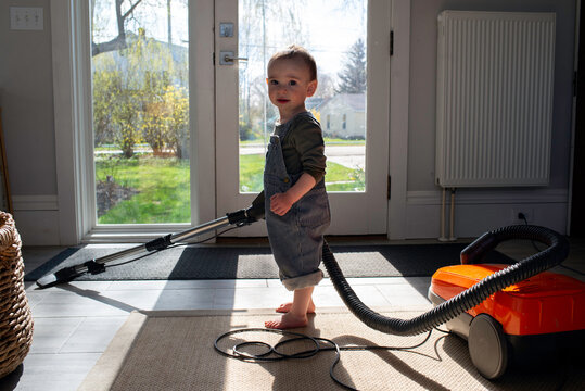 Cute Toddler Helping at Home by Vacuuming 