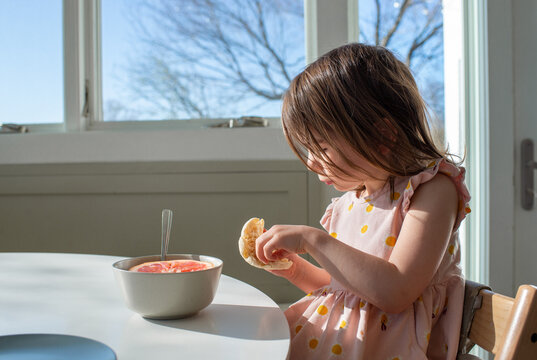 Child Eating Breakfast at the Kitchen Table at Home 