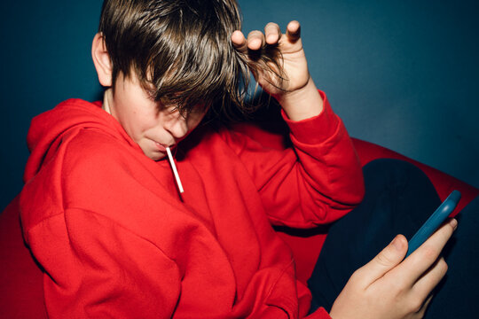 teen sitting in red chair on phone 