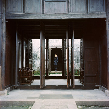 The girl stand in the middle of the gate of the ancient house