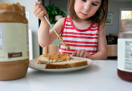 Child in Kitchen at Home Makes Herself a Peanut Butter Sandwich