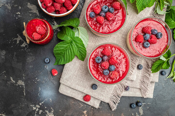 Raspberry Panna cotta with raspberry jelly on a dark background. Berry dessert with cream sauce in small jars. place for text
