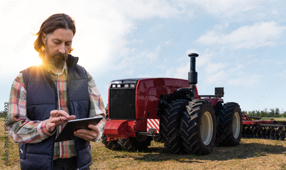 Poster farmer with digital tablet controls an autonomous tractor on a smart farm