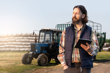 Farmer with a digital tablet on the background of an agricultural tractor	