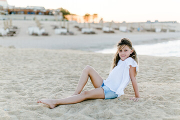 Fototapeta na wymiar Mädchen im Urlaub sitzt gemütlich am Strand