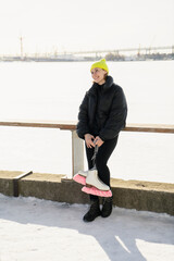 A woman stands hobby skating in winter in the park. Sportswear and a yellow warm hat.