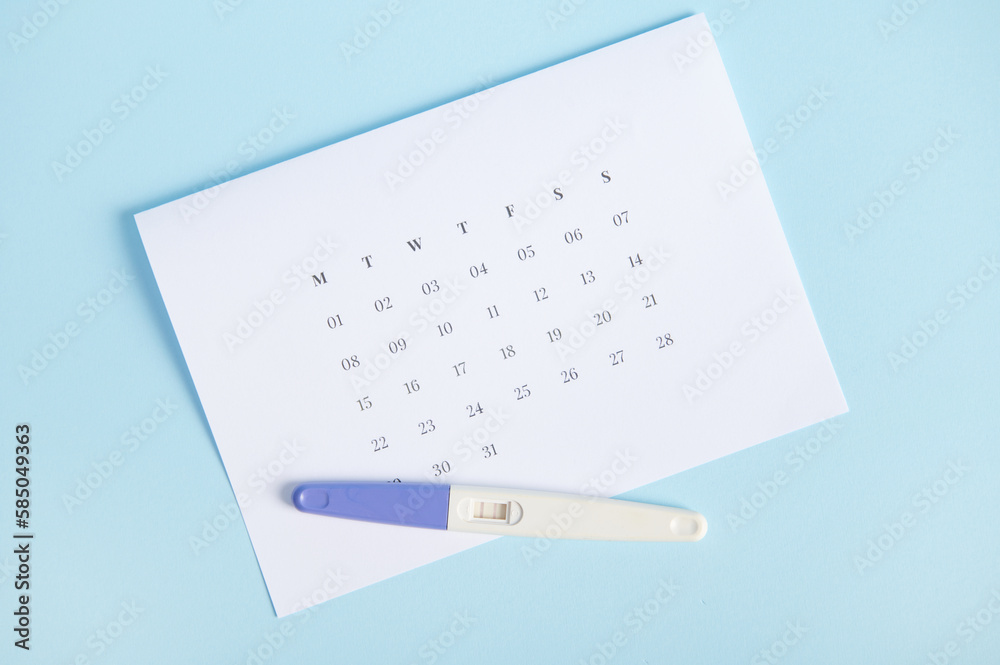 Wall mural inkjet pregnancy test showing two stripes on white clean calendar isolated on pastel blue background