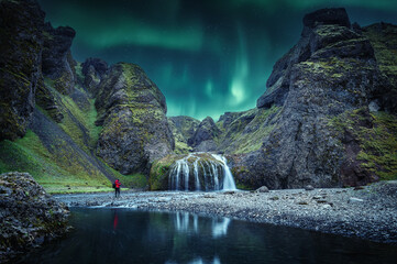 Icelandic Landscape. Scenic image of fairy-tale Stjornarfoss waterfall with Green northern lights....