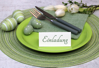 Tischdekoration zu Ostern mit Blumen,Ostereiern und einer Tischkarte mit dem Text Einladung.