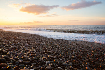 waves on the ocean at sunset against a purple sky