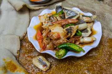 Meal in Ethiopia - pieces of fish with chilli peppers and vegetables