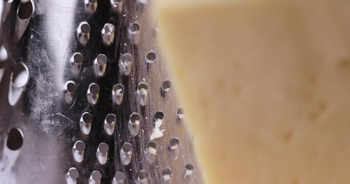 Hard cheese with holes grated into thin small slices, small pieces of cheese for pizza and snacks