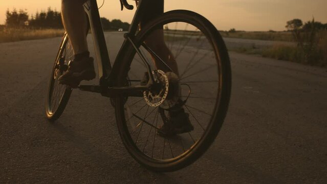 A man dressed in cycling clothes starting riding a modern bicycle on the asphalt out-of-town bicycle path. Active sporty people concept image