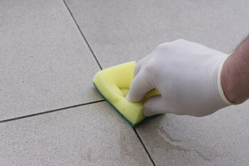 Man's hand in a glove protecting the joint between the balcony tiles with a chemical agent after...