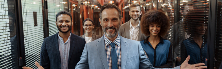 Group of happy, motivated business people standing together at office with their leader