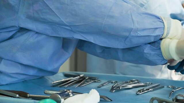 Preparation for the surgery. Surgery tools. Multiple surgery tools on the table in operating room. Scrub nurse hands in rubber gloves. Modern medical concept.