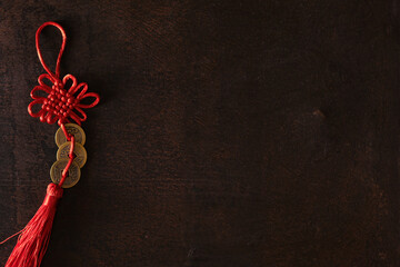 Chinese lucky coins with artfully tied knots for good fortune and success, on dark rusty background...