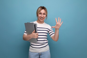 close up photo of smart blond female student in casual outfit with laptop showing five fingers on blue background with copy space