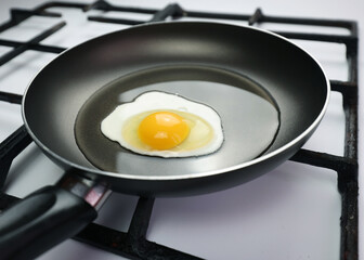 Frying pan on the stove. Cooking breakfast, homemade egg. Kitchen, egg, breakfast. White clean gas stove. Black pan with oil. Fried egg. Protein and yolk