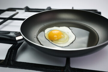 Frying pan on the stove. Cooking breakfast, homemade egg. Kitchen, egg, breakfast. White clean gas stove. Black pan with oil. Fried egg. Protein and yolk