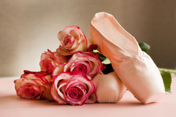new ballet slippers lying on pink background with roses. elegant ballet shoes bouquet. beauty dance © Julia