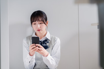 スマホを見ながら落ち込む女子高生