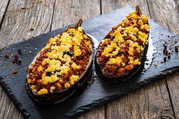 Roasted aubergine stuffed with minced meat and cheese  on wooden table