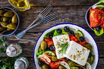 Fresh vegetable salad with feta cheese on wooden table
