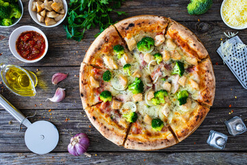 Circle pizza broccoli with chicken nuggets and mozzarella cheese on wooden table
