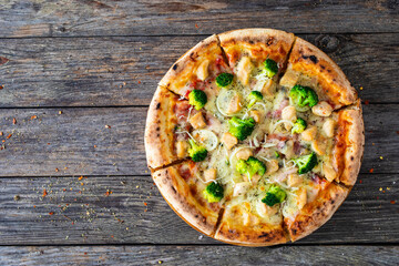 Circle pizza broccoli with chicken nuggets and mozzarella cheese on wooden table
