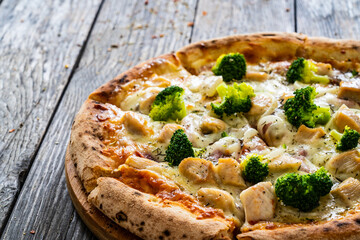 Circle pizza broccoli with chicken nuggets and mozzarella cheese on wooden table
