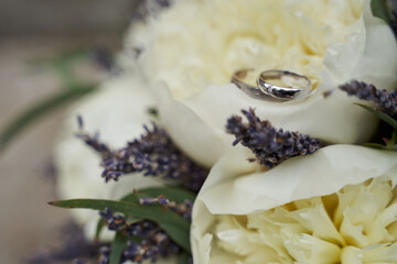 Fototapeta na wymiar close-up of beautiful wedding rings on a delicate bridal bouquet of large white peonies and lavender